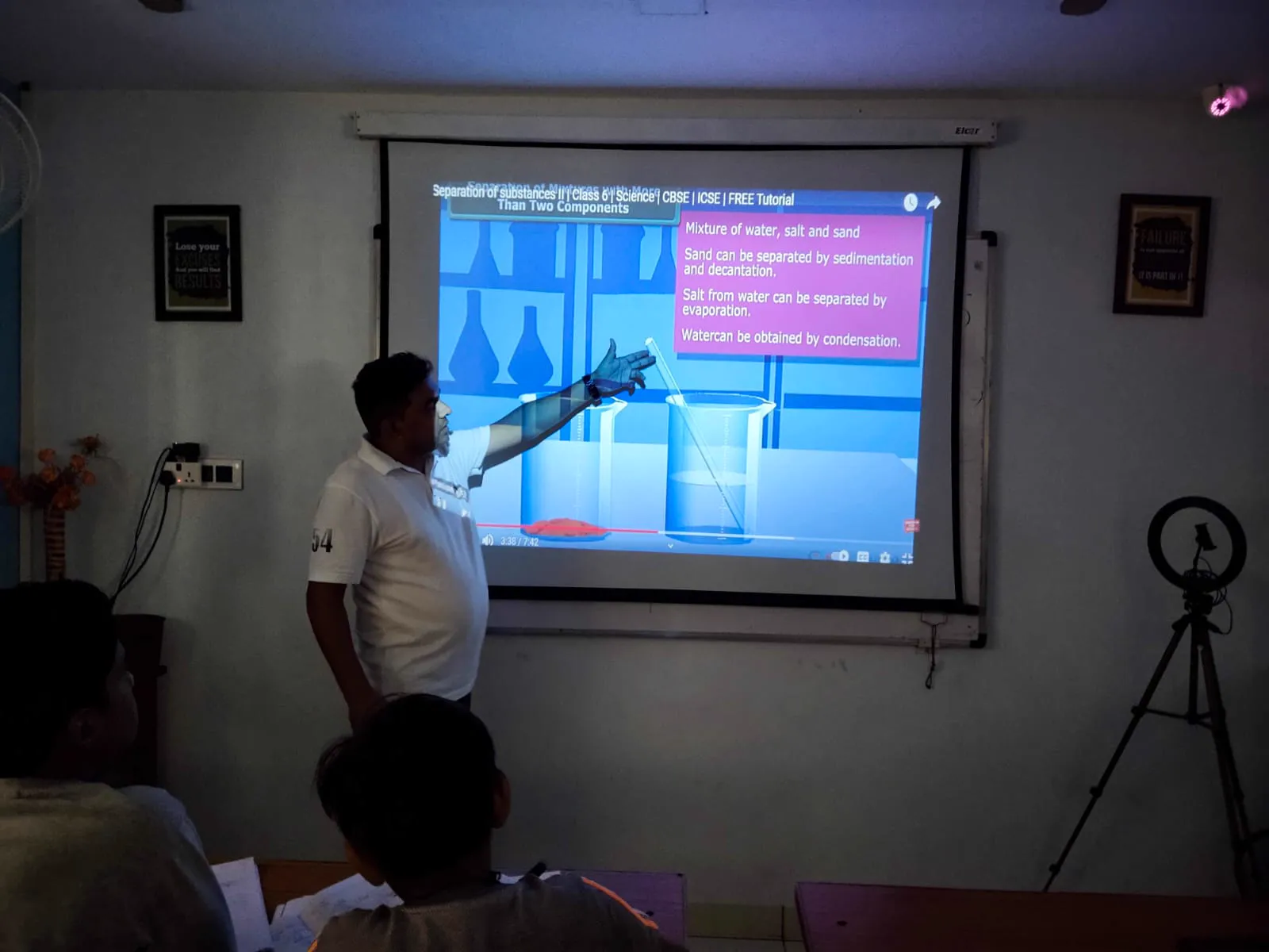 Manish Parmar teaching a science lesson on the projector to students at Ronak Coaching Center
